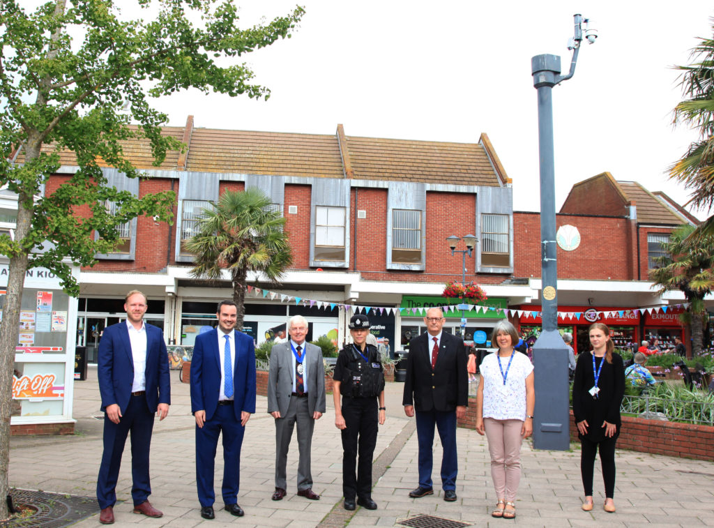 Pictured in front of one of the CCTV cameras sited in the Magnolia Centre: (From left to right) Ross Johnstone - Wireless CCTV Ltd. (WCCTV) Simon Jupp – Member of Parliament for East Devon Jeff Trail BEM – Chairman - Devon County Council Inspector Antonia Weeks – Devon and Cornwall Police Councillor Fred Caygill – Chairman of Exmouth Town Council CCTV Working Group Lisa Bowman and Mollie Carey – Exmouth Town Council